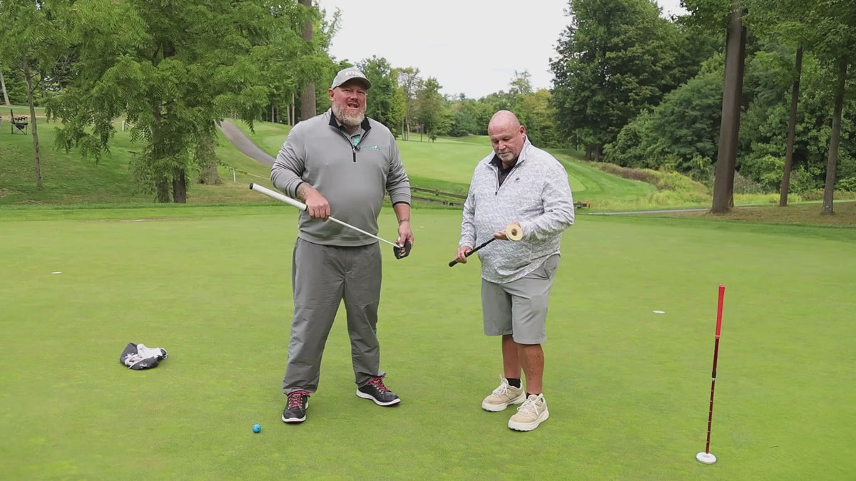 Load video: Golf professional Dan Steen and Pure Line Putting designer Michael Irvin stand on a putting green demonstrating the Pure Line Training Aid and Moment Zero Putter. Dan discusses using the Training Aid with students and the benefits of the Moment Zero Putter.